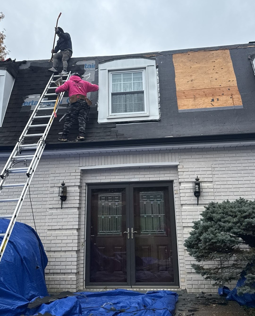 Workers repairing roof with ladders.